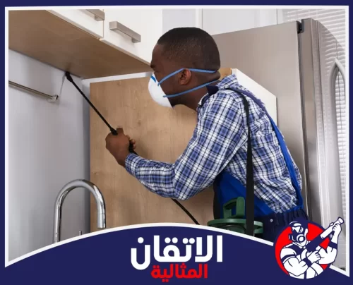شركة إبادة الحشرات بالظهران 0567008659 أتقان المثالية فني مكافحة الحشرات بالظهران يفحص خزائن المطبخ ويرش أماكن اختباء الصراصير خلف الدواليب.