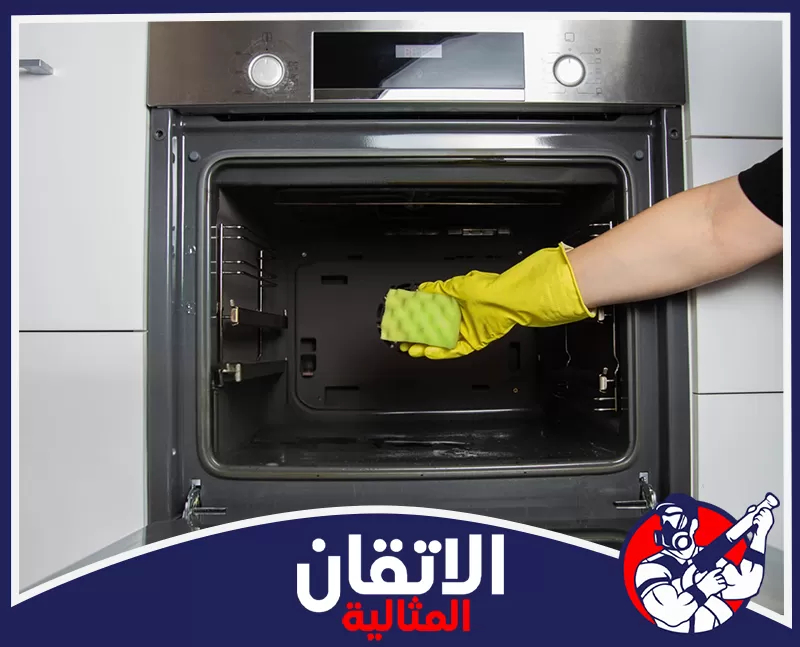 صيانة افران البا في الظهران 0567008659 شركة الإتقان المثالية تنظيف الفرن بإسفنجة ومنظف مناسب، مع ارتداء قفاز أصفر لحماية اليدين وإزالة الدهون والرواسب المتراكمة.